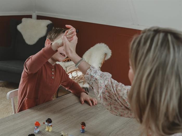 Yanieke werkt aan tafel met een kind, met poppetjes op tafel.