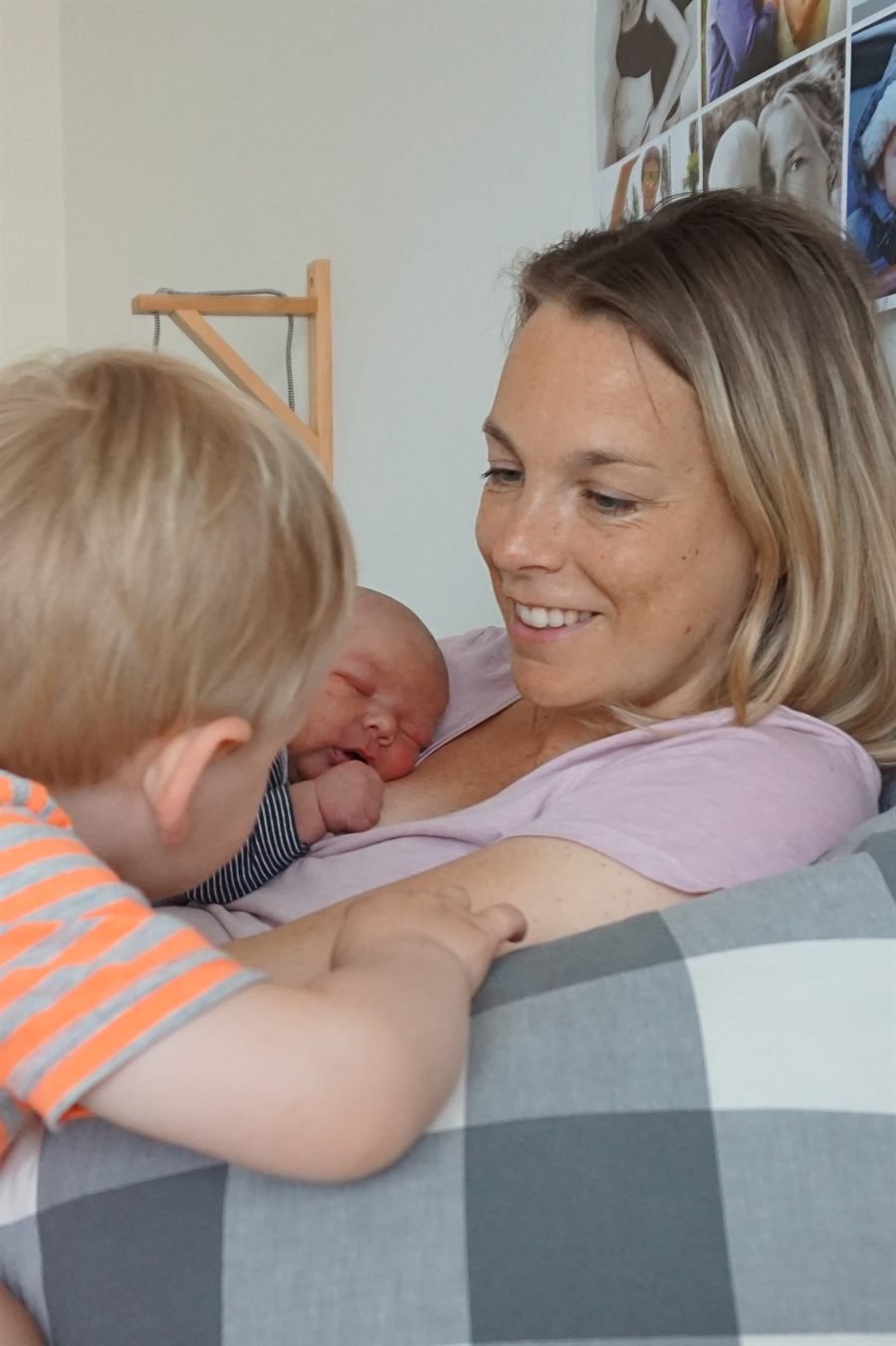 Yanieke ligt met haar pasgeboren baby op haar borst, terwijl haar oudste kindje tegen haar aan leunt.